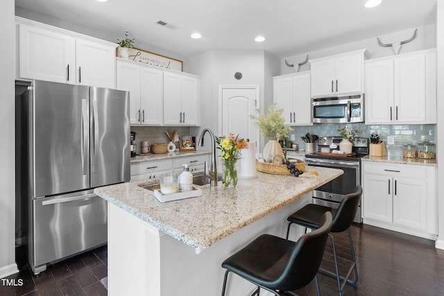 7807 Elmshire Way, Raleigh, NC 27616 - kitchen with stainless steel appliances, decorative backsplash, white cabinetry, a breakfast bar area, and recessed lighting