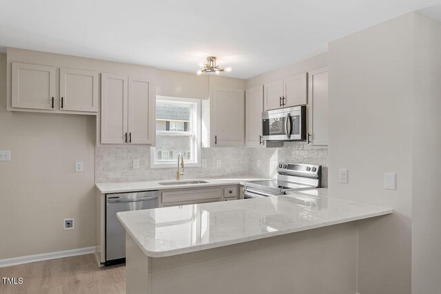 391 E Williams St, Angier, NC 27501 - kitchen featuring stainless steel appliances, a sink, a peninsula, decorative backsplash, and light stone counters