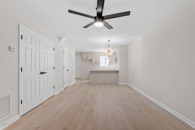 391 E Williams St, Angier, NC 27501 - unfurnished living room with a ceiling fan, light wood-style flooring, a chandelier, and baseboards