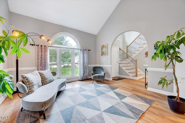 113 Fetzer Ct, Cary, NC 27513 - sitting room featuring wood finished floors, high vaulted ceiling, stairs, arched walkways, and baseboards