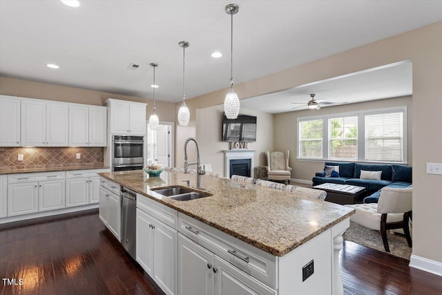 2333 Lantern Walk Ln, Wake Forest, NC 27587 - kitchen with a sink, open floor plan, a fireplace, appliances with stainless steel finishes, and dark wood finished floors