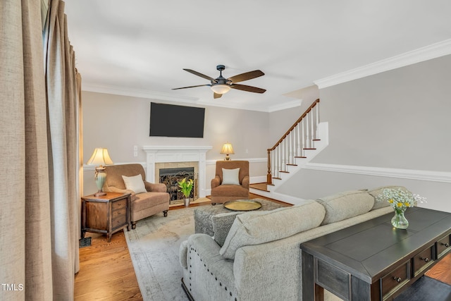 227 Paraggi Ct, Clayton, NC 27527 - living area featuring a ceiling fan, crown molding, light wood-type flooring, a tile fireplace, and stairway