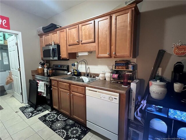 621 Marshtree Ln Unit 303, Fayetteville, NC 28314 - kitchen with appliances with stainless steel finishes, a sink, light tile patterned floors, brown cabinets, and dark countertops