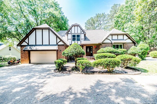 259 Golf Dr, Sanford, NC 27332 - tudor house featuring driveway, brick siding, a garage, and roof with shingles