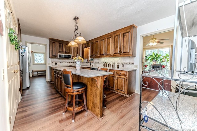 259 Golf Dr, Sanford, NC 27332 - kitchen featuring stainless steel appliances, light countertops, light wood-style floors, a kitchen bar, and a kitchen island