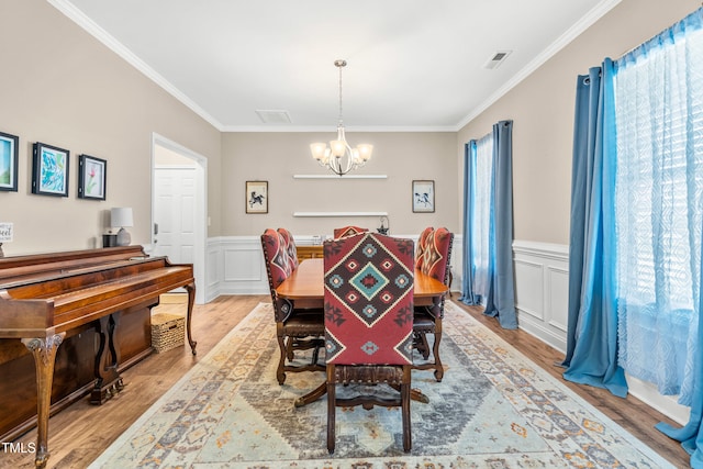 137 Clydes Point Way, Wendell, NC 27591 - dining space featuring a chandelier, ornamental molding, light wood finished floors, wainscoting, and a decorative wall