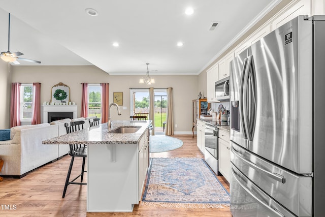 137 Clydes Point Way, Wendell, NC 27591 - kitchen with stainless steel appliances, a sink, an island with sink, white cabinets, and a breakfast bar