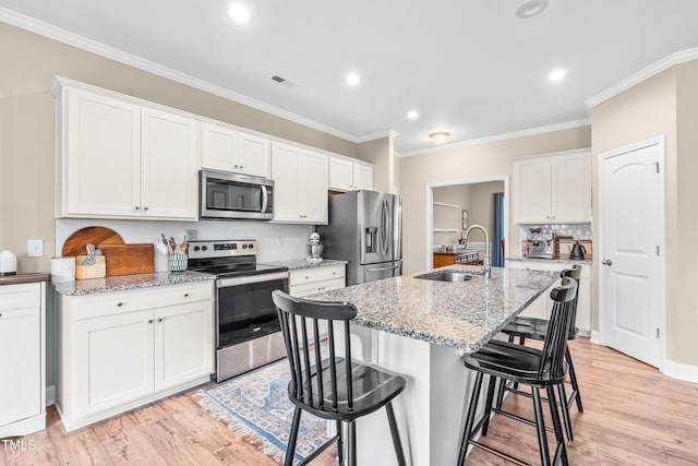137 Clydes Point Way, Wendell, NC 27591 - kitchen featuring appliances with stainless steel finishes, a sink, a breakfast bar area, tasteful backsplash, and light wood finished floors