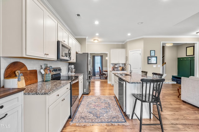 137 Clydes Point Way, Wendell, NC 27591 - kitchen with stainless steel appliances, a kitchen breakfast bar, ornamental molding, light wood-type flooring, and white cabinets