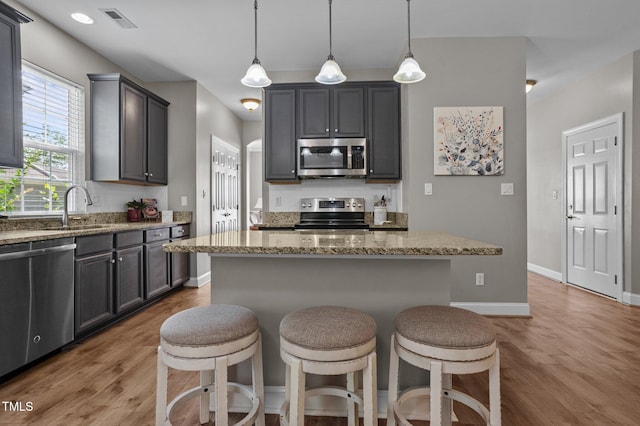 648 Long Melford Dr, Rolesville, NC 27571 - kitchen with appliances with stainless steel finishes, light stone counters, wood finished floors, a breakfast bar, and a sink