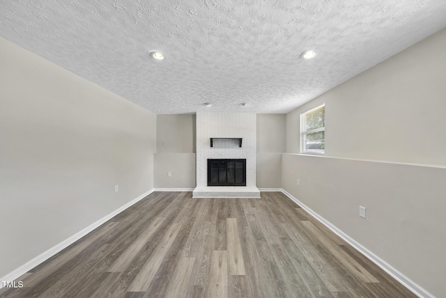 5529 Wood Pond Ct, Raleigh, NC 27610 - unfurnished living room featuring a brick fireplace, a textured ceiling, wood finished floors, baseboards, and recessed lighting