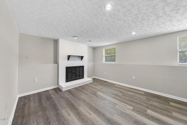 5529 Wood Pond Ct, Raleigh, NC 27610 - unfurnished living room featuring a textured ceiling, a fireplace, wood finished floors, baseboards, and recessed lighting