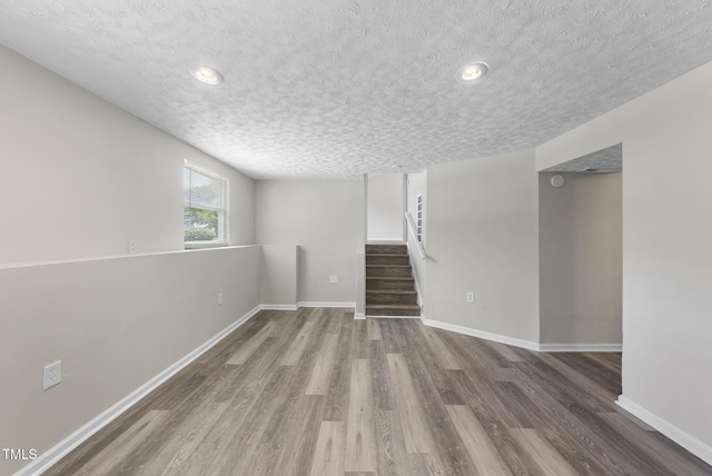 5529 Wood Pond Ct, Raleigh, NC 27610 - below grade area featuring a textured ceiling, stairway, wood finished floors, baseboards, and recessed lighting