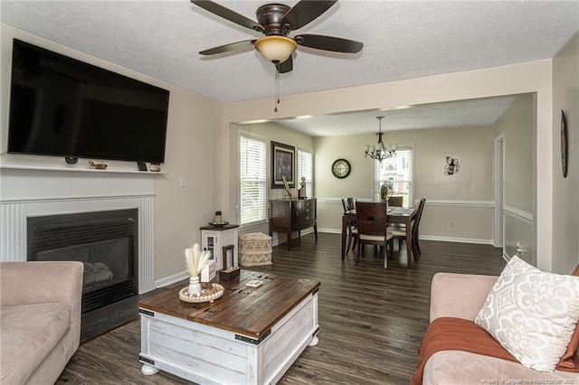 3538 Gables Dr, Fayetteville, NC 28311 - living room featuring dark wood-style flooring, baseboards, a ceiling fan, a glass covered fireplace, and a chandelier