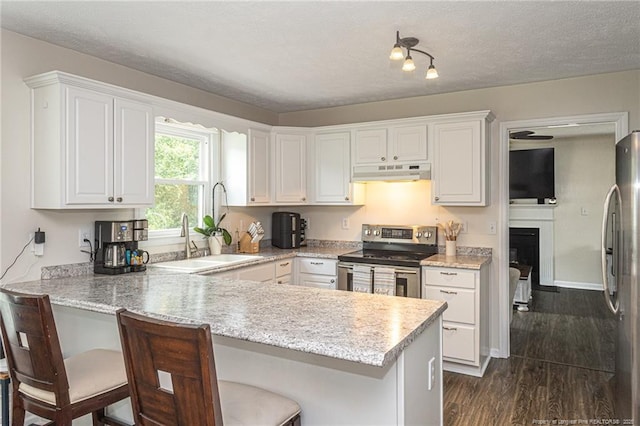 3538 Gables Dr, Fayetteville, NC 28311 - kitchen with appliances with stainless steel finishes, under cabinet range hood, a peninsula, white cabinetry, and dark wood finished floors