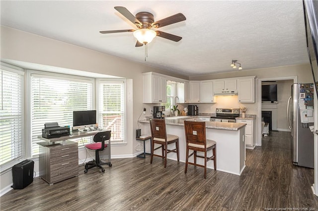 3538 Gables Dr, Fayetteville, NC 28311 - kitchen with appliances with stainless steel finishes, a peninsula, under cabinet range hood, a desk, and dark wood finished floors