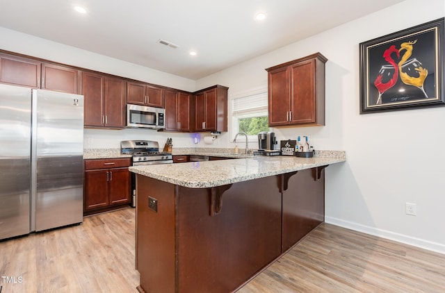 150 Sherrill Place Ln, Garner, NC 27529 - kitchen featuring stainless steel appliances, light wood-type flooring, a peninsula, a breakfast bar, and recessed lighting