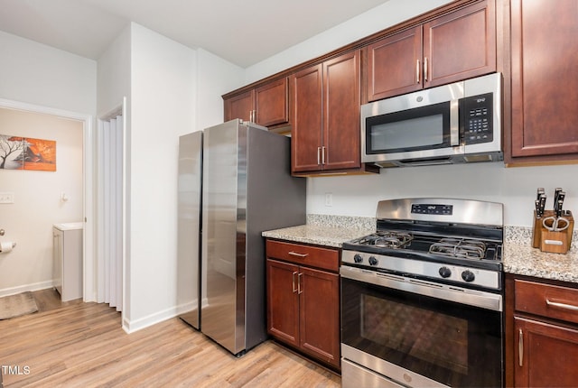 150 Sherrill Place Ln, Garner, NC 27529 - kitchen featuring appliances with stainless steel finishes, light wood-style flooring, and light stone countertops