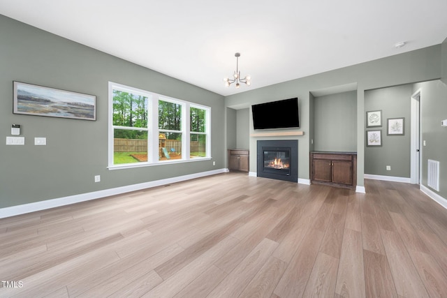 20 Scotland Dr, Youngsville, NC 27596 - unfurnished living room featuring a chandelier, light wood-style floors, a glass covered fireplace, and baseboards
