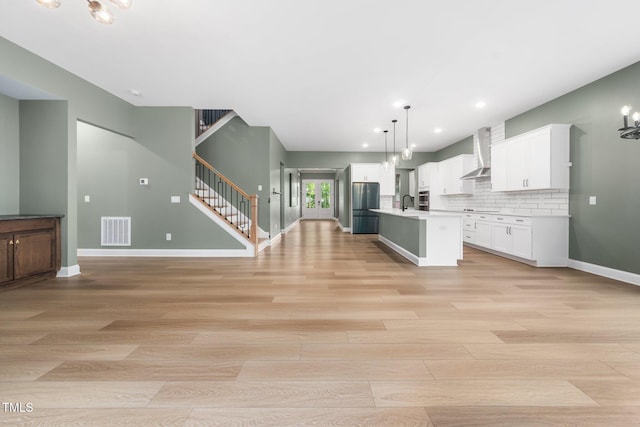 20 Scotland Dr, Youngsville, NC 27596 - kitchen with wall chimney exhaust hood, appliances with stainless steel finishes, light wood-style flooring, open floor plan, and white cabinets
