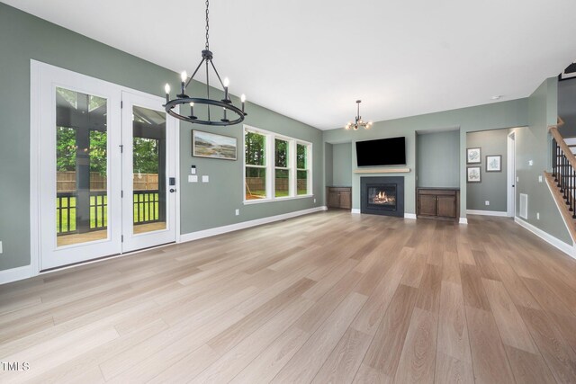 20 Scotland Dr, Youngsville, NC 27596 - unfurnished living room featuring a chandelier, light wood-style floors, stairway, a warm lit fireplace, and baseboards