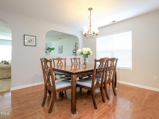 3515 Mountain Brook Cir, Durham, NC 27704 - dining area featuring arched walkways, a chandelier, light wood-type flooring, and baseboards