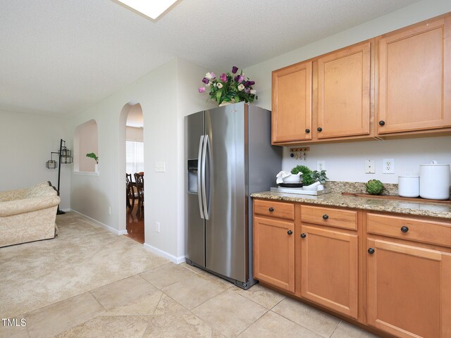 3515 Mountain Brook Cir, Durham, NC 27704 - kitchen featuring stainless steel fridge, arched walkways, light colored carpet, light stone countertops, and baseboards