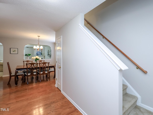 3515 Mountain Brook Cir, Durham, NC 27704 - dining space with arched walkways, stairway, a chandelier, light wood-style flooring, and baseboards