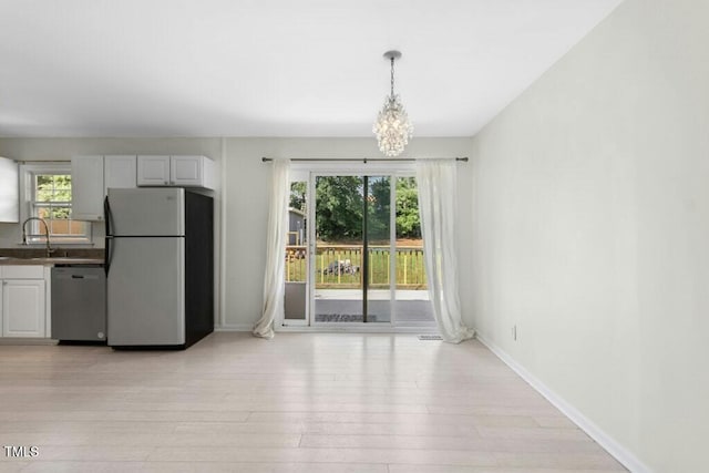 4021 Chaucer Dr, Durham, NC 27705 - unfurnished dining area featuring a chandelier, light wood finished floors, a sink, and baseboards