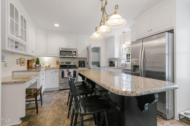 1115 Laurel Ln NW, Wilson, NC 27896 - kitchen featuring appliances with stainless steel finishes, white cabinetry, a center island, a breakfast bar, and glass insert cabinets