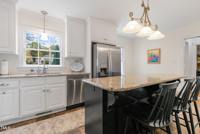 1115 Laurel Ln NW, Wilson, NC 27896 - kitchen featuring stainless steel appliances, a sink, a breakfast bar area, white cabinets, and ornamental molding