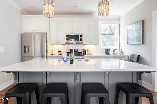 595 E Cabarrus St, Raleigh, NC 27601 - kitchen with appliances with stainless steel finishes, a chandelier, crown molding, a center island with sink, and white cabinetry
