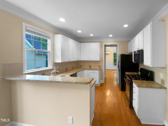 3116 Kirby St, Durham, NC 27713 - kitchen with range with gas cooktop, black microwave, a peninsula, light stone counters, and white cabinets