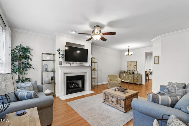 222 Ashton Hall Ln, Raleigh, NC 27609 - living room with a ceiling fan, light wood finished floors, ornamental molding, a fireplace with flush hearth, and a chandelier