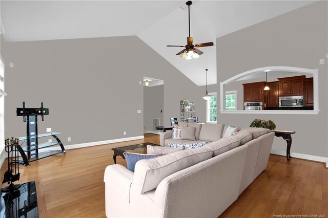 3207 Notting Hill Rd, Fayetteville, NC 28311 - living room featuring a ceiling fan, light wood-style flooring, high vaulted ceiling, arched walkways, and baseboards