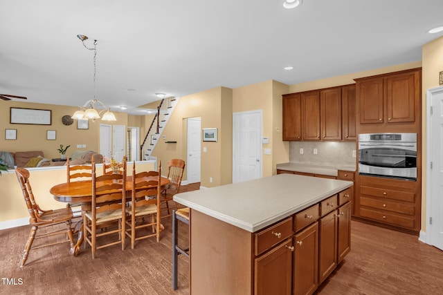 1428 White Opal Dr, Knightdale, NC 27545 - kitchen featuring stainless steel oven, open floor plan, a center island, wood finished floors, and light countertops