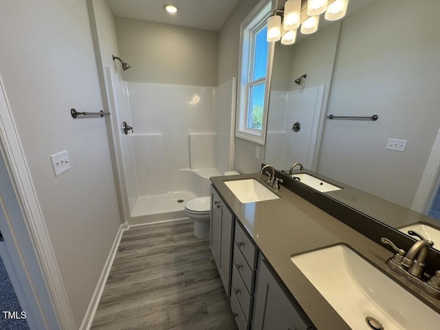 140 Brookhaven Dr, Spring Hope, NC 27882 - bathroom with a walk in shower, toilet, wood finished floors, double vanity, and baseboards