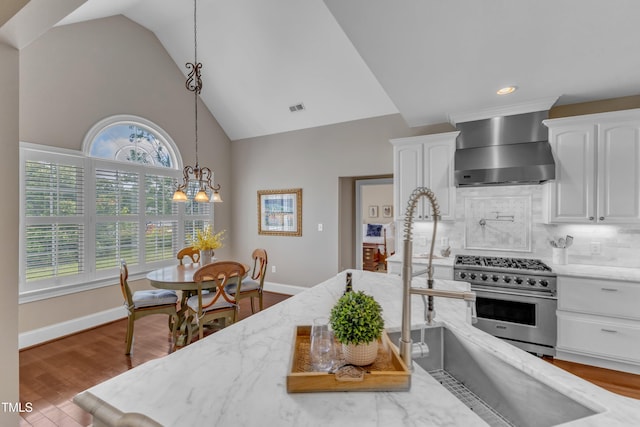 7800 Twin Pines Way, Fuquay Varina, NC 27526 - kitchen with wall chimney exhaust hood, luxury stove, light stone counters, white cabinetry, and backsplash