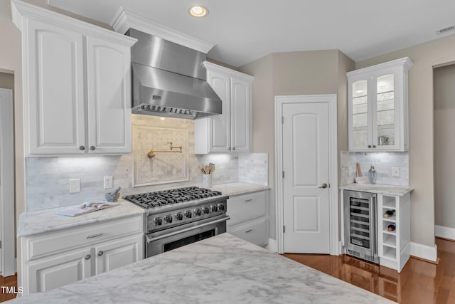 7800 Twin Pines Way, Fuquay Varina, NC 27526 - kitchen with wall chimney range hood, high end stainless steel range oven, white cabinetry, light stone counters, and glass insert cabinets