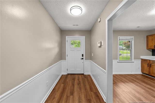 2308 Keith Dr, Raleigh, NC 27610 - doorway featuring wood finished floors, a textured ceiling, and a wainscoted wall