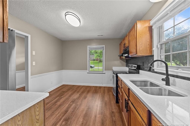 2308 Keith Dr, Raleigh, NC 27610 - kitchen with electric range, a sink, brown cabinetry, dark wood-style floors, and exhaust hood