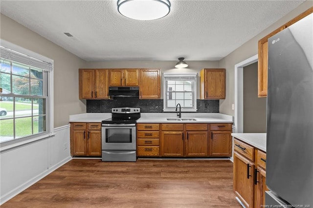 2308 Keith Dr, Raleigh, NC 27610 - kitchen featuring appliances with stainless steel finishes, range hood, a sink, brown cabinets, and a textured ceiling