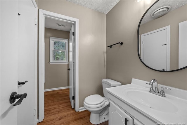 2308 Keith Dr, Raleigh, NC 27610 - half bath with vanity, wood finished floors, toilet, baseboards, and a textured ceiling