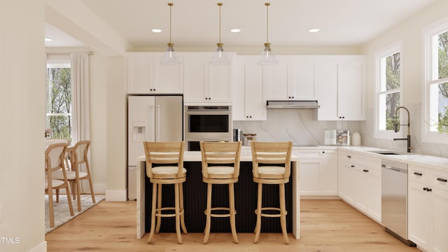 2940C Chapel Hill Rd, Durham, NC 27707 - kitchen featuring appliances with stainless steel finishes, a sink, under cabinet range hood, light wood-type flooring, and white cabinetry