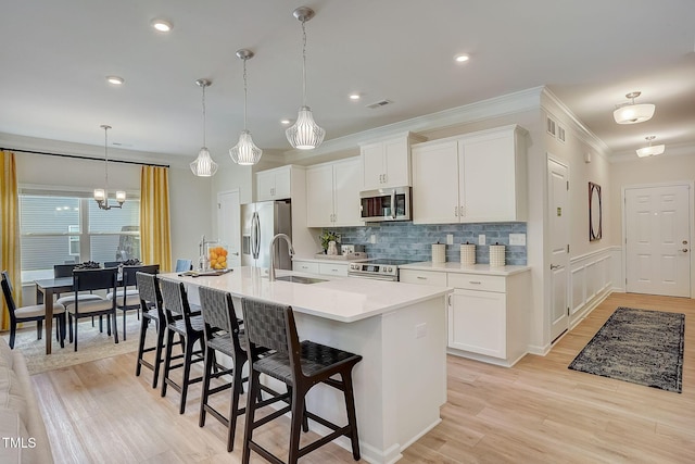 128 Bruce Dr, Dunn, NC 28334 - kitchen featuring appliances with stainless steel finishes, a sink, a breakfast bar area, a kitchen island with sink, and light countertops