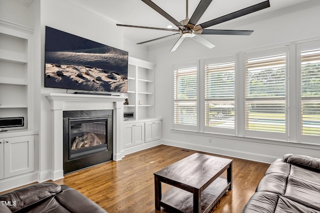 6250 Moinear Ln, Chapel Hill, NC 27514 - living area with built in shelves, crown molding, ceiling fan, a glass covered fireplace, and wood finished floors