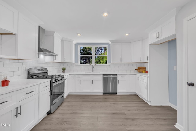 305 W Canary St, Dunn, NC 28334 - kitchen featuring stainless steel appliances, wall chimney exhaust hood, white cabinetry, a sink, and tasteful backsplash