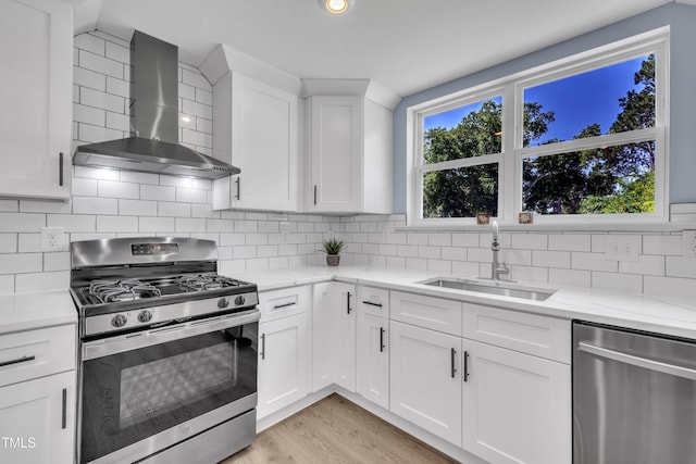 305 W Canary St, Dunn, NC 28334 - kitchen with stainless steel appliances, wall chimney exhaust hood, a sink, light wood finished floors, and white cabinets