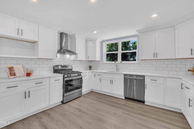 305 W Canary St, Dunn, NC 28334 - kitchen featuring wall chimney exhaust hood, appliances with stainless steel finishes, a sink, white cabinets, and light wood finished floors