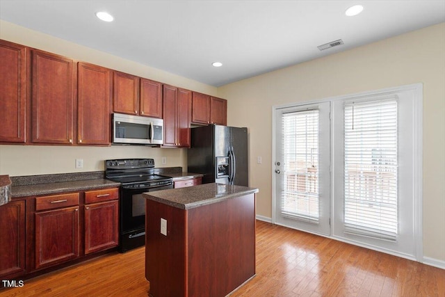 229 Michigan Ave, Cary, NC 27519 - kitchen with black appliances, dark countertops, a kitchen island, wood finished floors, and baseboards